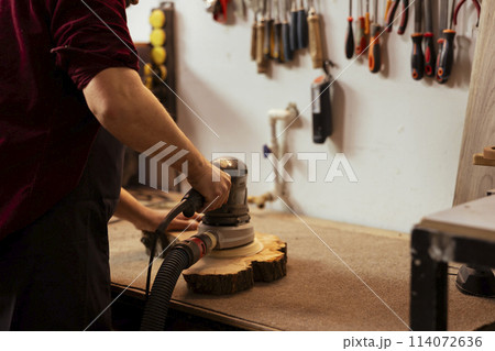 Carpenter using orbital sander with finer sandpaper grits to achieve smoother and more refined finish. Woodworker using angle grinder on wood, achieving professional quality results Carpenter using orbital sander with finer sandpaper grits to achieve smoother and more refined finish. Woodworker using angle grinder on wood, achieving professional quality results 114072636