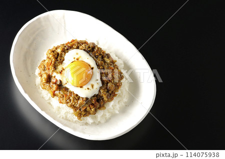 卵黄、焦がしチーズ乗せキーマカレーを黒背景で俯瞰撮影 114075938