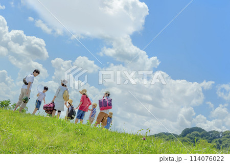 夏の草地を歩く行楽の2家族 114076022