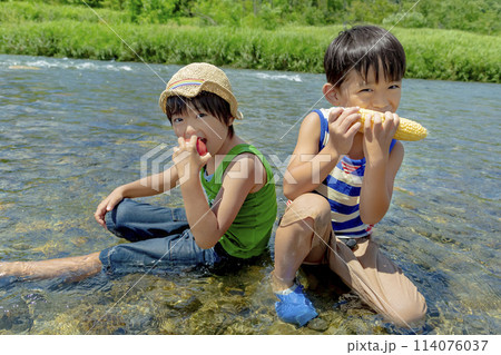 夏の川原で夏野菜を持つ男の子たち 114076037