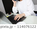 パソコン前で電話をする女性 114076122