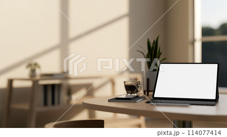 A white-screen digital tablet mockup and decor on a wooden table in a cozy minimalist cafe. 114077414