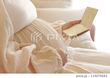 通帳を見つめる妊婦 114078843