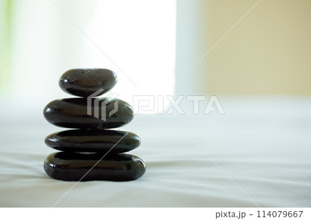Balanced perfectly in a spa environment, a stack of smooth black stones creates tranquil atmosphere, enhancing the sense of focus and relaxation 114079667