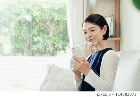 リビングでスマートフォンを操作する主婦 114082073