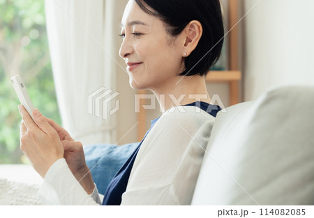 リビングでスマートフォンを操作する主婦 114082085