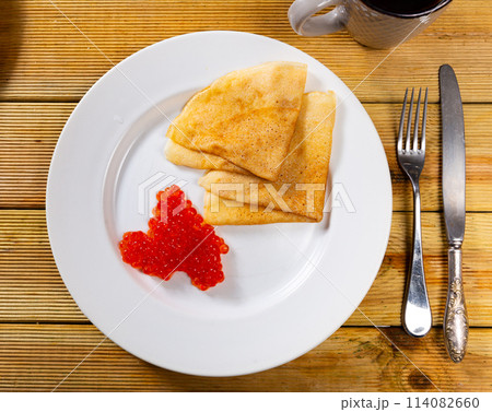 Pancakes with red caviar dished up in service plate. Traditional Russian cuisine 114082660