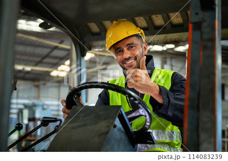 forklift driver sits in his vehicle in a warehouse and gives a thumbs up to show confidence in his work forklift driver sits in his vehicle in a warehouse and gives a thumbs up to show confidence in his work 114083239