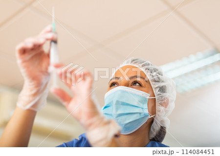Female nurse in mask prepared a syringe for injection Female nurse in mask prepared a syringe for injection 114084451