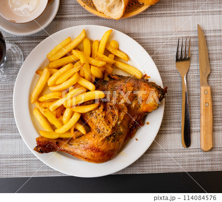 French fries and piece of fried chicken is served on large white platter 114084576