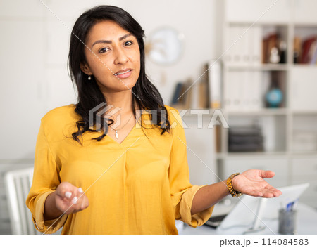 Happy smiling Latin American businesswoman standing in office 114084583