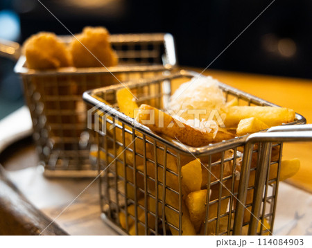 Two baskets of finger food french fries and chicken nuggets on a table Two baskets of finger food french fries and chicken nuggets on a table 114084903