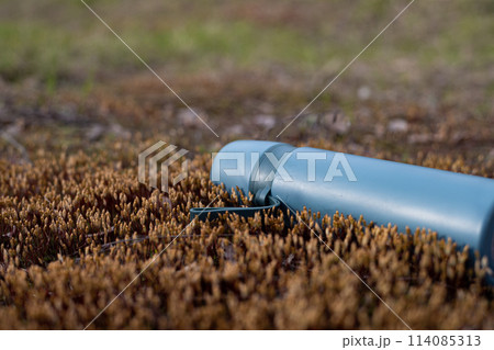 A Close-Up of a Blue Water Bottle Resting on Rustic Terrain 114085313