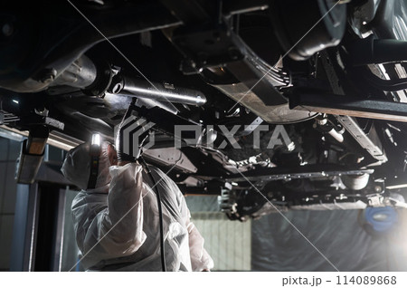 The master sprays an anti-corrosion compound on the bottom of the car. The master sprays an anti-corrosion compound on the bottom of the car. 114089868