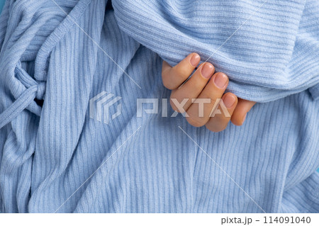 Woman manicured hands, stylish beige nails. Closeup of manicured nails of female hand in blue sweater in blue background. Winter or autumn style of nail design concept Woman manicured hands, stylish beige nails. Closeup of manicured nails of female hand in blue sweater in blue background. Winter or autumn style of nail design concept 114091040