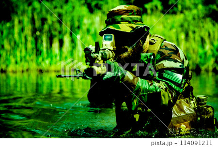 A focused soldier standing the marshland with his rifle, submerging himself, his arms and rifle visible, harsh military service half-length shot A focused soldier standing the marshland with his rifle, submerging himself, his arms and rifle visible, harsh military service half-length shot 114091211