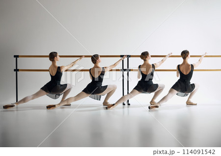 Ballet practice at barre. Teen girls, ballet dancers in black costumes training, preparing for performance against grey studio background Ballet practice at barre. Teen girls, ballet dancers in black costumes training, preparing for performance against grey studio background 114091542