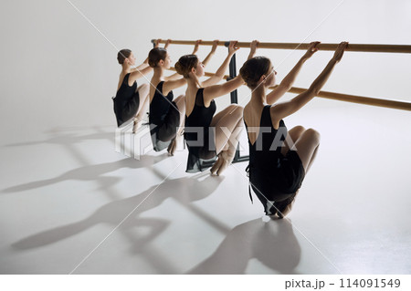 Discipline and determination. Tender teen girls, ballet dancers in black costumes attending dance class, training against grey studio background 114091549