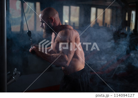 Bald Caucasian Bodybuilder doing heavy triceps exercises with cable. Bald Caucasian Bodybuilder doing heavy triceps exercises with cable. 114094127