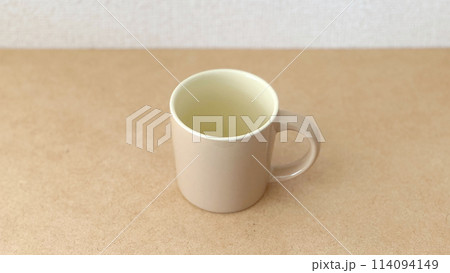 シンプルな背景に置いたベージュ色のコップ シンプルな背景に置いたベージュ色のコップ 114094149