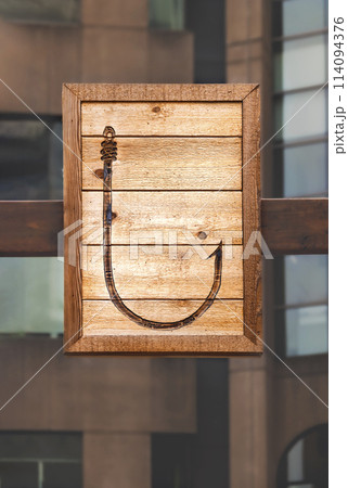 A large fishing hook is depicted on a wooden plank 114094376