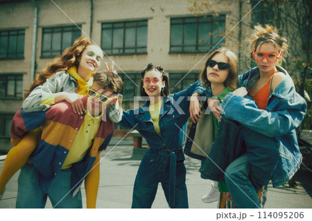 Joyful urban fashion vibe. Lively group of five friends enjoy sunny day on rooftop, wearing stylish denim clothes. Carefree, youthful spirit 114095206