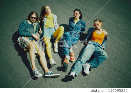 Denim clothes. Group of friends wearing stylish 90s inspired outfits, posing on rooftop, having fun and joy. 114095222