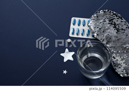 Sleep mask, pills and glass on blue background, space for text 114095509