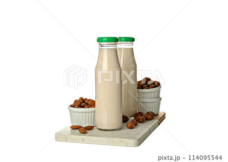 PNG, Bottles of milk and nuts in bowls on board, isolated on white background 114095544