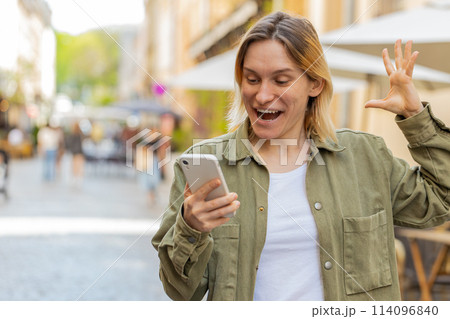 Happy young girl tourist using smartphone celebrating win good message news on urban city street Happy young girl tourist using smartphone celebrating win good message news on urban city street 114096840