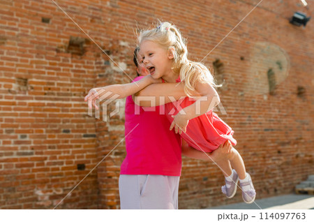 Blonde little girl with cochlear implant playing with her mother outdoor. Hear impairment deaf and health concept. Disability and inclusion. Copy space 114097763