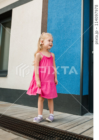 Child girl walks and have fun outdoor with cochlear implant on the head. Hearing aid and treatment concept. Inclusion and disability Child girl walks and have fun outdoor with cochlear implant on the head. Hearing aid and treatment concept. Inclusion and disability 114097978