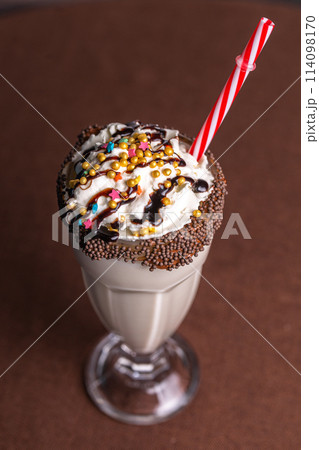 sweet milkshake with a tube on a brown background 114098170