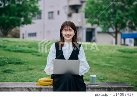 公園でパソコンを操作する若い女性 公園でパソコンを操作する若い女性 114098417