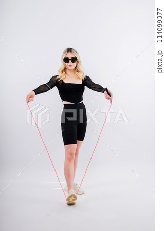 Beautiful fitness female posing on studio background with jumping rope Beautiful fitness female posing on studio background with jumping rope 114099377