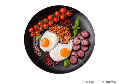 English breakfast with fried eggs, bacon, beans, tomatoes, spices and herbs 114100258