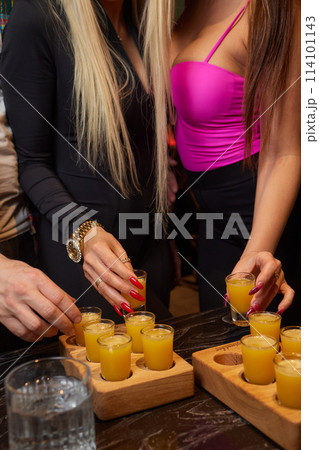 Group cheers with shot glasses of Paulaner hefeweizen wheat beer at fun event 114101143