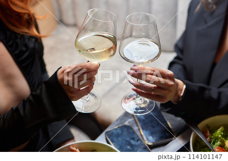 A woman holds a cocktail in her hand, with her fingers wrapped around the glass A woman holds a cocktail in her hand, with her fingers wrapped around the glass 114101147