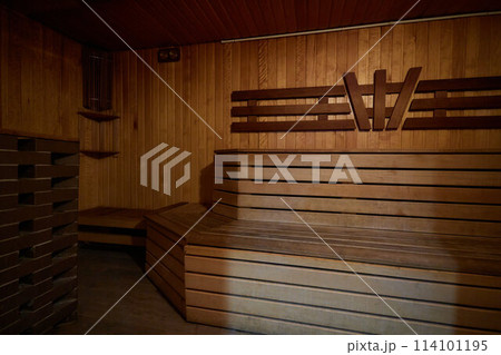 A hardwood sauna with a plank ceiling, brick wall, and stairs 114101195