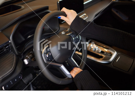 Hand of woman holding steering wheel of car Hand of woman holding steering wheel of car 114101212