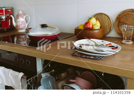 used dirty dishes on wooden kitchen countertop, with built-in dishwasher 114101356