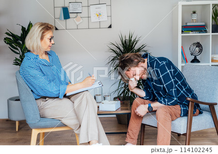 Depressed male patient having psychotherapy session with counselor at mental health clinic. Man with emotional problems consulting professional therapist i comfy office. Psychological help service. Depressed male patient having psychotherapy session with counselor at mental health clinic. Man with emotional problems consulting professional therapist i comfy office. Psychological help service. 114102245
