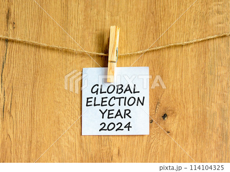 Global election year 2024 symbol. Concept words Global election year 2024 on beautiful white paper on clothespin. Beautiful wooden background. Business Global election year 2024 concept. Copy space 114104325