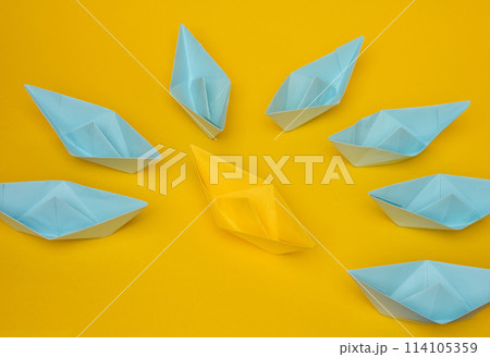 A group of blue paper boats surrounded one yellow boat, the concept of bullying 114105359