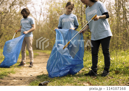 Diverse people collecting rubbish and storing in the trash disposal bag, picking up junk and plastic bottles to help with pollution. Clearing the forest, ecosystem protection. Diverse people collecting rubbish and storing in the trash disposal bag, picking up junk and plastic bottles to help with pollution. Clearing the forest, ecosystem protection. 114107168