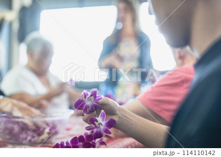 ハワイ、ワイキキにて蘭のレイ作りを体験する若者 114110142