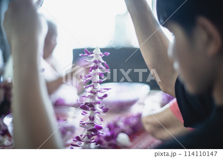 ハワイ、ワイキキにて蘭のレイ作りを体験する若者 114110147