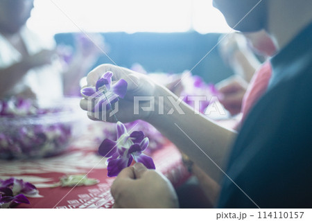 ハワイ、ワイキキにて蘭のレイ作りを体験する若者 114110157