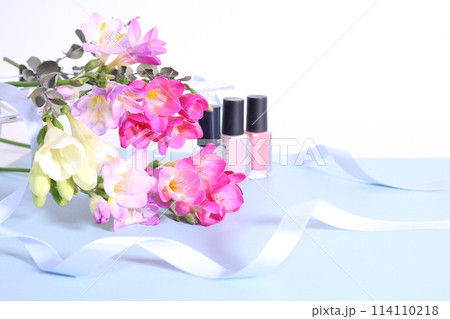 カールしたブルーのリボンとカラフルなフリージアの花束とマニキュア カールしたブルーのリボンとカラフルなフリージアの花束とマニキュア 114110218