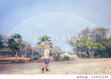虹のアーチに向かって歩く男性 114111144